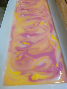 Orange, yellow and pink soap in the mold with a little bit of white with swirls.