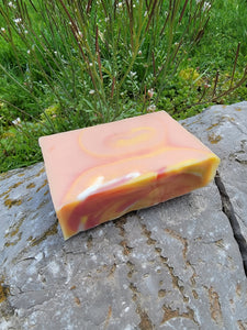 Orange, yellow and pink soap with a little bit of white with swirls.