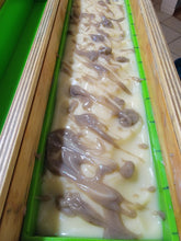 Hot chocolate soap sitting in the mold.  Soap is white on top with a chocolate drizzle and glitter. 