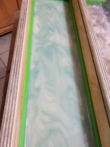 White tea and sage soap in the mold, white and green swirls.