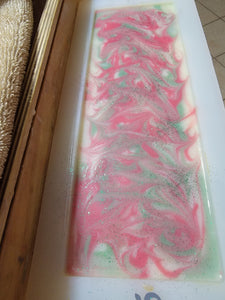 White soap with red and green swirls with green glitter on top sitting in the soap mold.