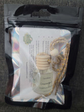 Black holographic mylar bag with instructions inside and a glass car diffuser bottle with a wooden lid and a string to hang it.  Cracklin Birch scent.
