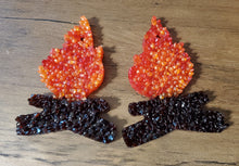 Two campfire hanging air fresheners.  Campfire part is orange and red and bottom is brown.