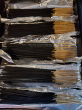 Incense sticks being dipped sitting on a tray in foil.