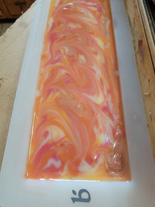 Orange, dark pink and white swirled soap in the mold.